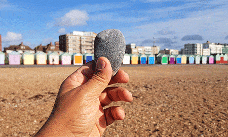 holding up a pebble over the Pebbles on the beach in Brighton UK